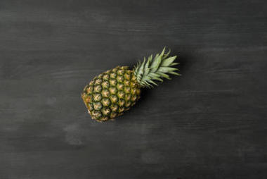 顶视图新鲜成熟的菠萝在黑暗的桌面