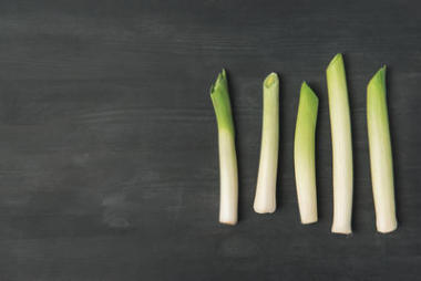 顶部的观点安排新鲜韭菜在黑暗的桌面上