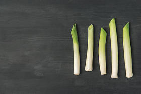 顶部的观点安排新鲜韭菜在黑暗的桌面上