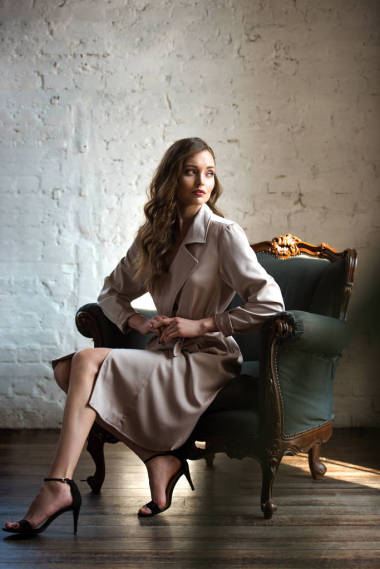 優(yōu)雅的女人在經(jīng)典的風(fēng)衣擺在扶手椅