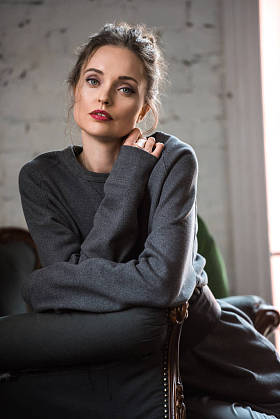 美丽温柔的黑发女孩坐在扶手椅上, 看着相机的肖像