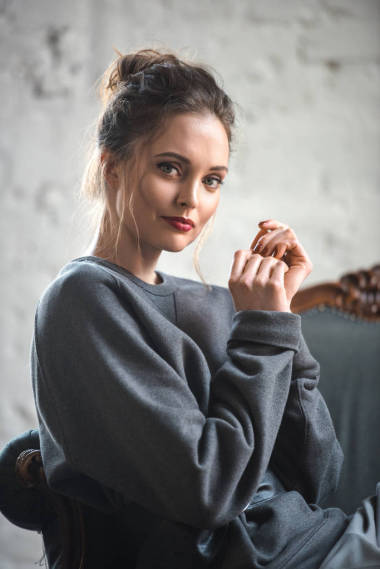 有魅力的黑发女子穿着时髦的衣服坐在扶手椅上, 微笑着拍照