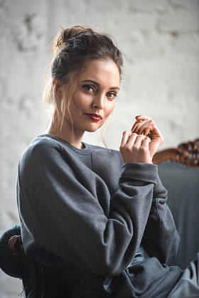 有魅力的黑发女子穿着时髦的衣服坐在扶手椅上, 微笑着拍照