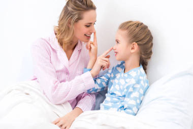 母親和女兒在家里用手指撫摸鼻子的側(cè)面視圖