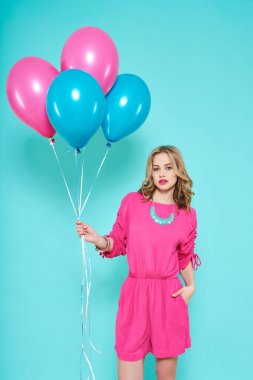 华丽时髦的年轻女子在派对服装手持一束气球淡蓝色背景上的生日派对概念 华丽时髦的年轻女子在派对服装手持一束气球淡蓝色背景上的生日派对概念