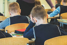 在学校上课累了的小学生。后退视图