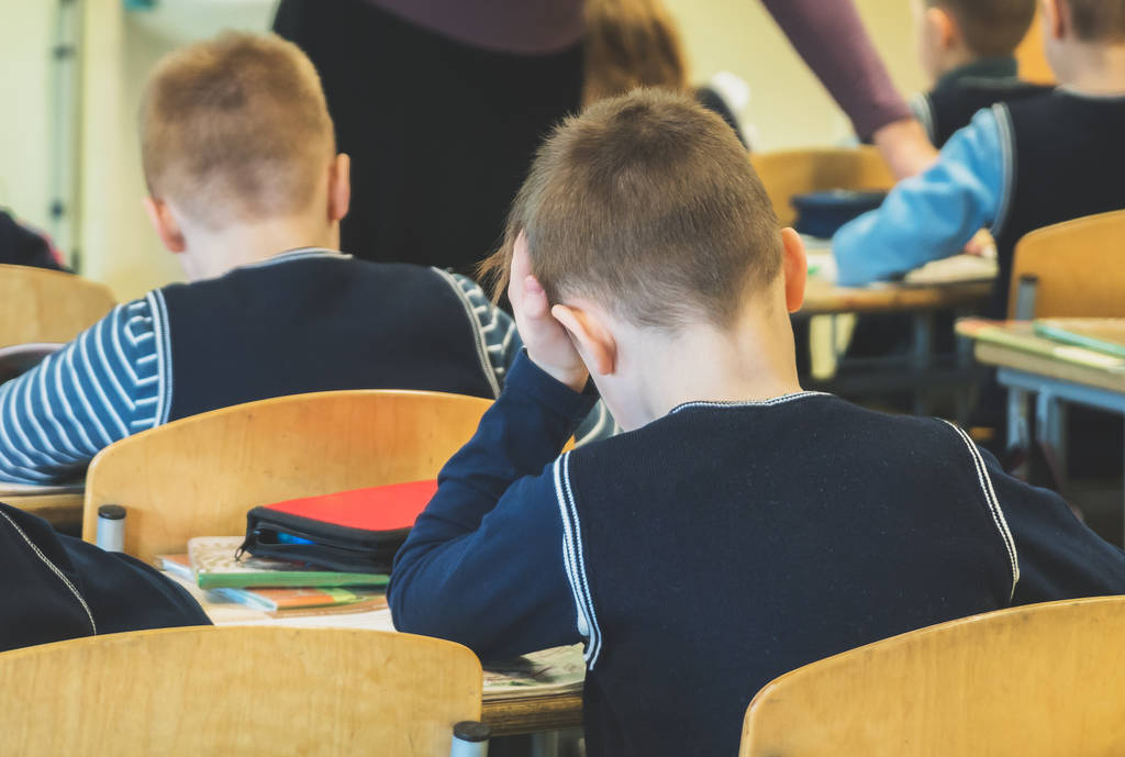 在学校上课累了的小学生。后退视图