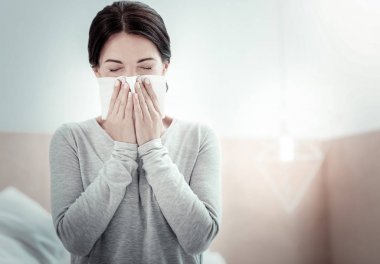 疲憊的生病的女人閉上眼睛打噴嚏