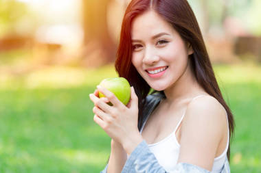 美丽的亚洲女性模特手拿绿色苹果在公园户外健康饮食有机食品水果饮食理念