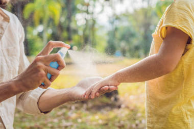 特寫鏡頭的爸爸和兒子使用蚊子噴霧。戶外噴灑驅(qū)蚊劑.