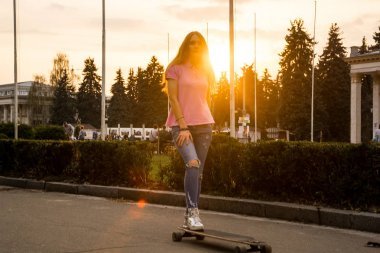 一個年輕女子夏天在公園里騎滑板。
