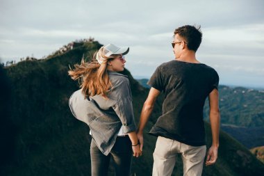 情侶坐在懸崖上的男人和女人輕松的山和云鳥(niǎo)瞰愛(ài)情和旅行的快樂(lè)情緒生活方式的概念。年輕家庭旅行活躍冒險(xiǎn)假期, 時(shí)髦