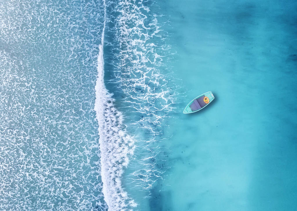 夏季时漂浮在蔚蓝海洋中的小船鸟瞰图 