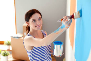 快乐微笑女人画室内墙上的新房子。幸福微笑的女人