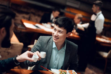 兩人在餐廳與中國商人舉行會議, 舉杯與咖啡杯敬酒