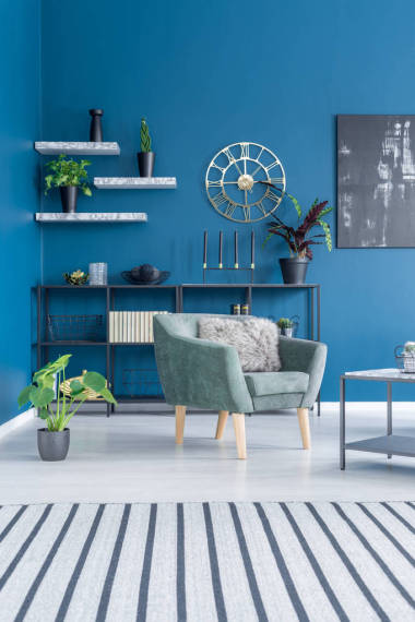 彩色起居室內(nèi)帶綠色扶手椅的條紋地毯與海軍藍(lán)墻