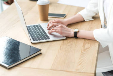 部分觀點(diǎn)的女實(shí)業(yè)家打字的筆記本電腦在工作場(chǎng)所與咖啡去和書在辦公室