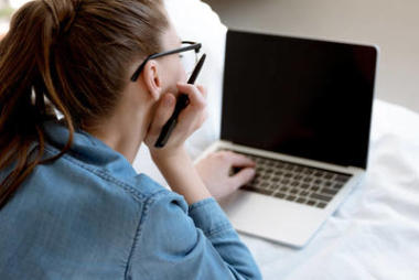 在臥室里使用筆記本電腦的年輕女性 teleworker 的后視圖