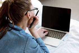在卧室里使用笔记本电脑的年轻女性 teleworker 的后视图
