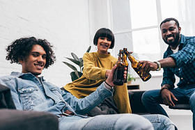 微笑的多元文化的年轻朋友无比的啤酒瓶