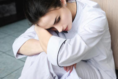 有吸引力的疲倦的廚師坐在地板在餐館廚房