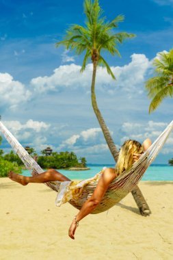 美麗的女人在海邊曬日光浴比基