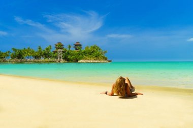 美麗的女人在海邊曬日光浴比基