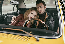 时尚体贴的年轻夫妇在皮革夹克坐在一起老式汽车