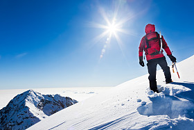 登山运动员到达顶部的雪山在阳光明媚的冬天