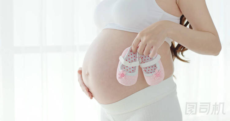 懷孕婦女站立和舉行小嬰兒鞋