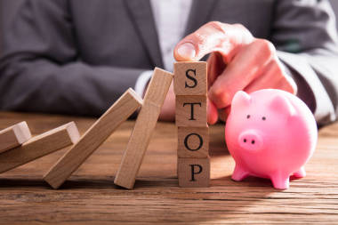 人的手指停止木塊阻止多米諾骨牌跌倒 Piggybank