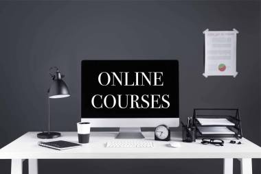 帶在線課程的臺式計算機在屏幕、商務(wù)圖表、時鐘和辦公用品的工作場所題詞