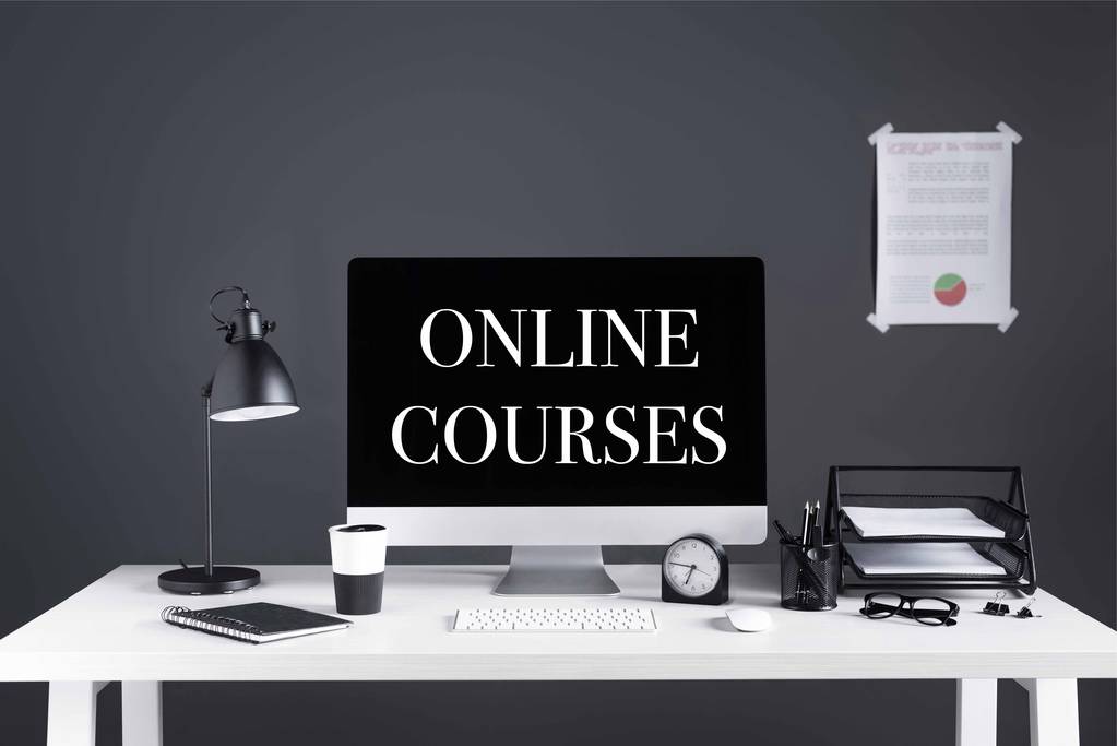 带在线课程的台式计算机在屏幕、商务图表、时钟和办公用品的工作场所题词 带在线课程的台式计算机在屏幕、商务图表、时钟和办公用品的工作场所题词