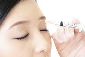 年轻女子在她的脸上注射美容