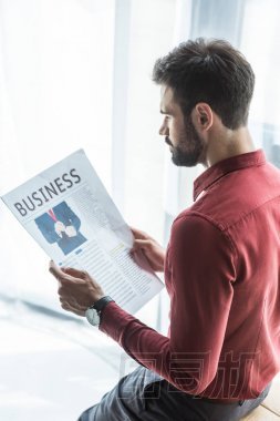 英俊的年輕商人在辦公室讀報紙