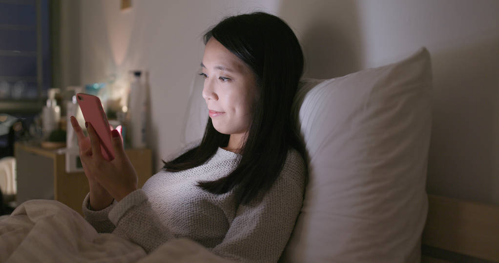晚上在家使用移动电话的妇女照片 晚上在家使用移动电话的妇女照片