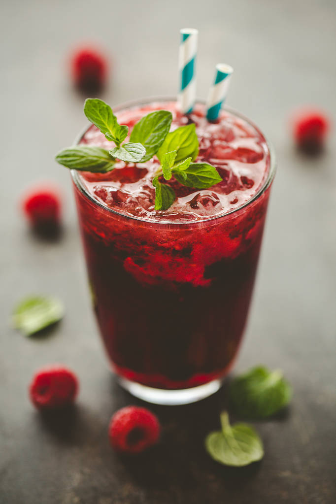 用稻草和薄荷叶盛满冰和新鲜覆盆子的玻璃 用稻草和薄荷叶盛满冰和新鲜覆盆子的玻璃