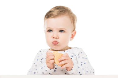 可愛的小男孩吃餅干和坐在高腳孤立的白色背景