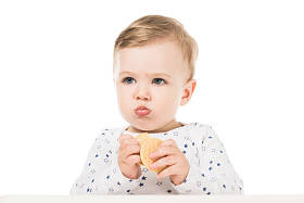 可爱的小男孩吃饼干和坐在高脚孤立的白色背景