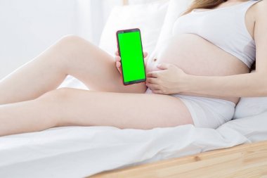 床上掛著綠色屏幕的孕婦