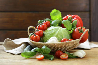 木桌上的篮子里的新鲜春天蔬菜