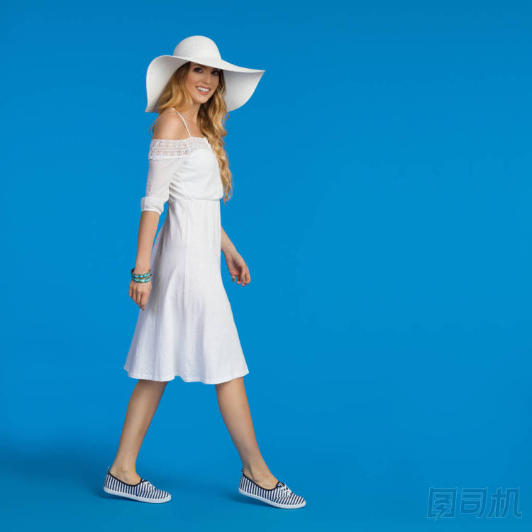 穿著白色夏季禮服, 運(yùn)動(dòng)鞋和太陽帽散步的女人。側(cè)面視圖