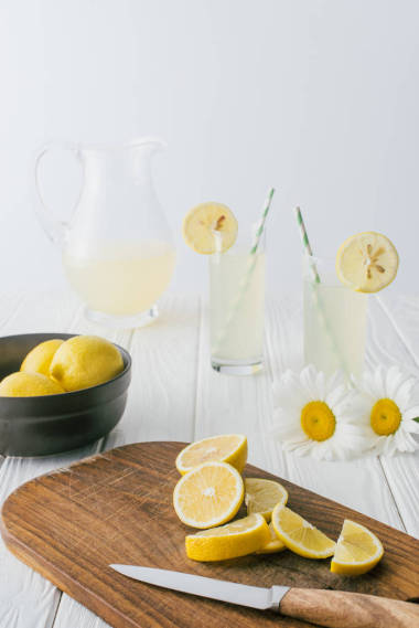 灰色背景下白色木質(zhì)玻璃上的雛菊和檸檬水的特寫圖