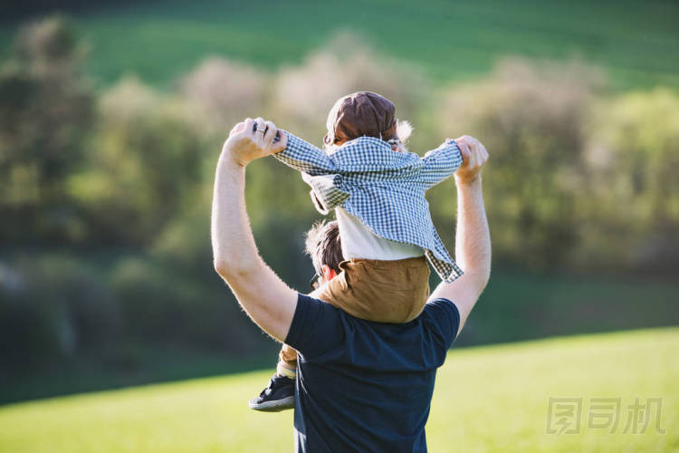 一個父親給蹣跚學(xué)步的孩子騎著車到外面去春季自然