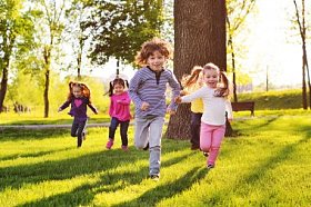 许多年幼的孩子微笑着沿着公园的草地奔跑