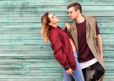 時尚情侶在他們的眼鏡與勃艮第衣服擺在藍色的木墻上