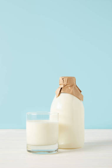 牛奶玻璃和牛奶在藍色背景紙包裝的瓶子特寫鏡頭 