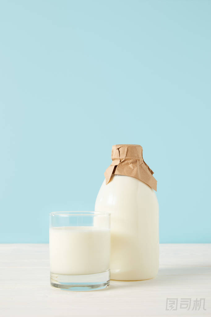 牛奶玻璃和牛奶在藍色背景紙包裝的瓶子特寫鏡頭 