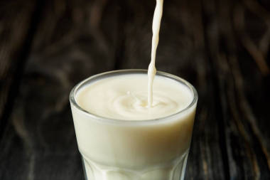 黑木表面牛奶倒入玻璃的特寫視圖