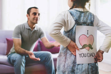 父亲节快乐的概念。儿童女儿隐藏惊喜明信片礼物给她的爸爸